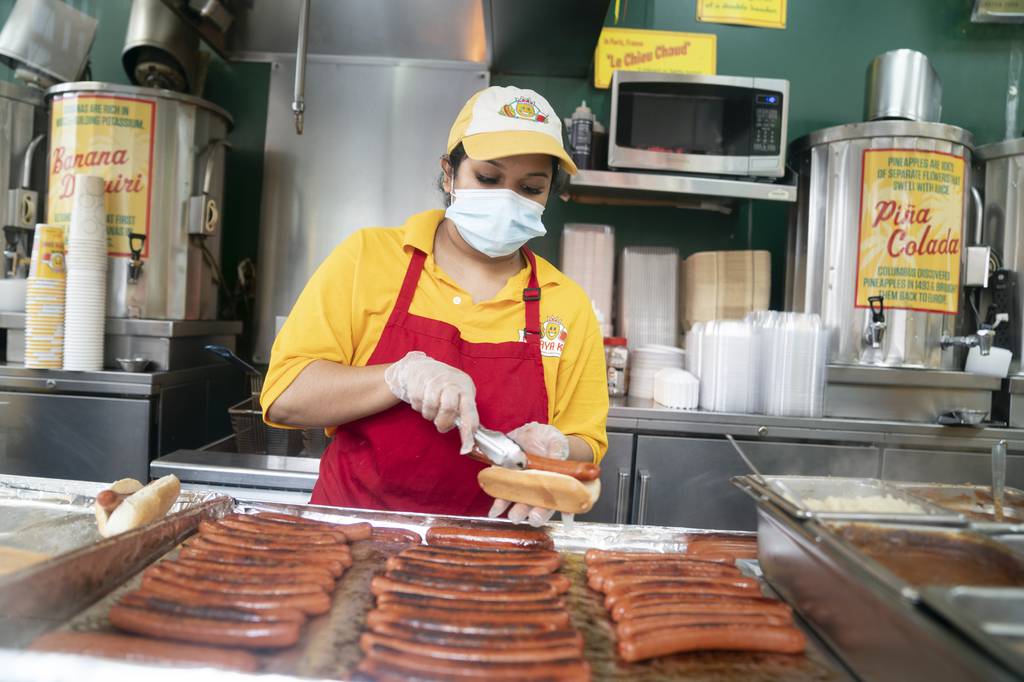 An employee of Papaya King, An Upper East Side staple, prepares a hotdog Friday, July 8, 2022 in Manhattan, New York.