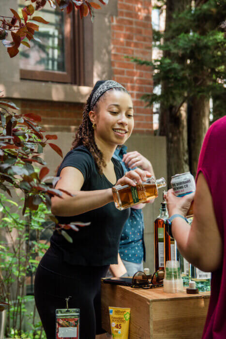 A woman pours a beverage for an attendee at the 2022 "Open Stages" music festival hosted by BKCM. 