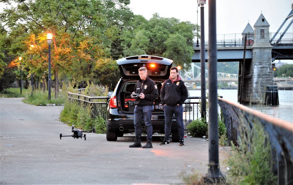 Two detectives from the NYPD TARU Unit prepare to deploy a drone to search for the second missing youth at the  Harlem River Park at West 143 street, on Thursday, May 18, 2023.