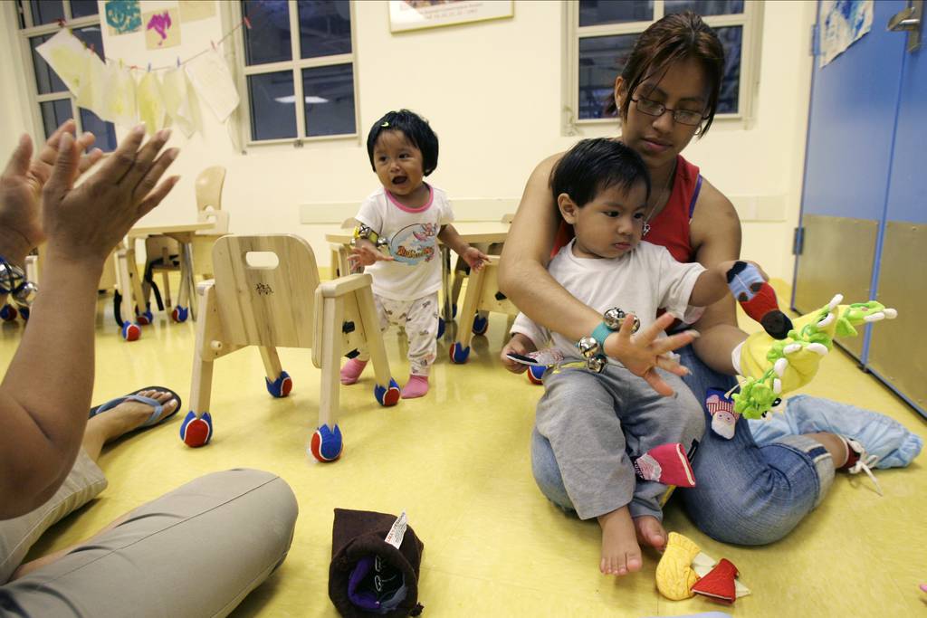 Teachers aid Laudes Hernandez, left, claps as she plays with Jocelyn Nava, center, while Jenny Gomez, right, plays with her son Brandon Garcia at Edward A. Reynolds West Side High School's  "LYFE Center"  Tuesday, Aug. 7, 2007 in New York. West Side is one of 40 high schools in New York that houses a day care center. It serves the babies and toddlers of students at the school - teen parents who are trying to stay on track while also raising little ones.   (AP Photo/Mary Altaffer)