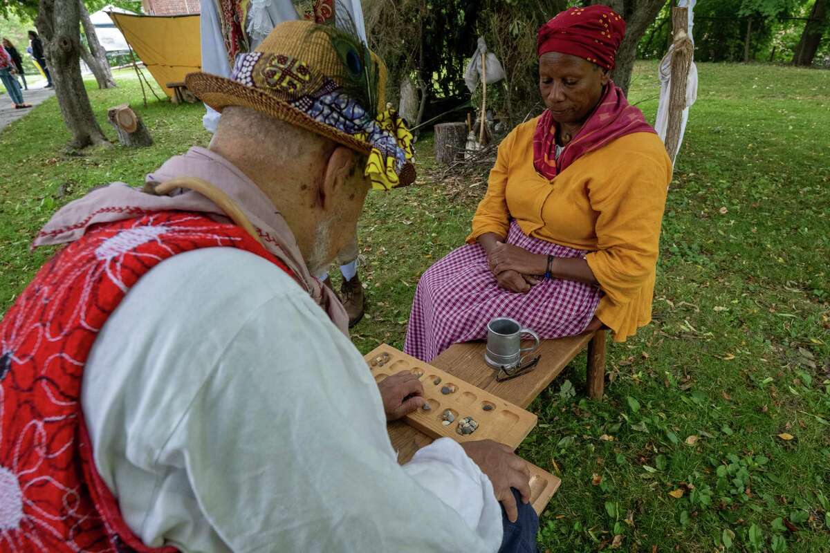 Lavada Nahon, right, and Chief Baba Neil Clarke play owari-mancala during Pinkster — which began as a Dutch holiday but became an African celebration of family, hope and cultural identity — on Saturday, June 3, 2023, at Schuyler Mansion in Albany, NY.