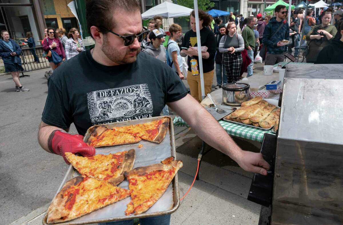 DeFazio’s employee Thomas Eaton warms up vegan pizza for a long line of customers as the Capital Region Vegan Network holds their annual Veg Out event featuring vegan food from area restaurants on Sunday, June 4, 2023 in Troy, N.Y.