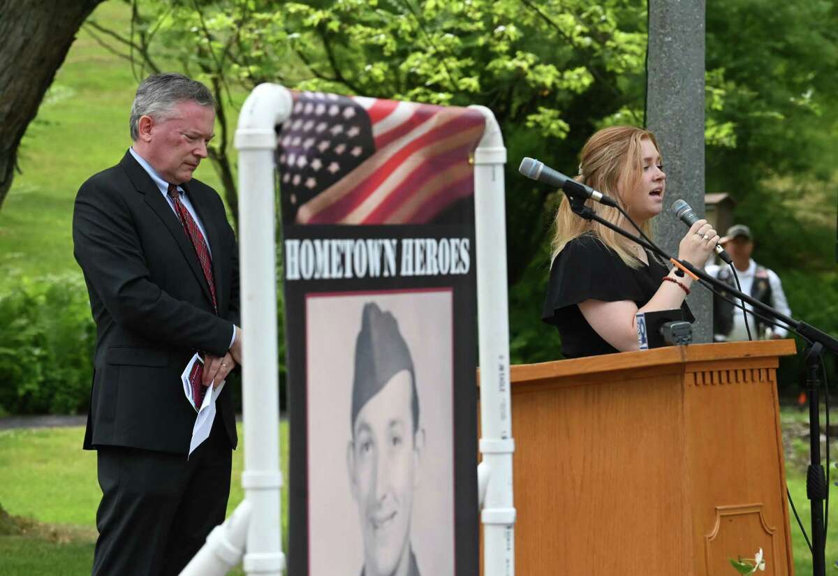 Guilderland Supervisor Peter Barber, left, lowers his head during the singing of the "Star-Spangled Banner" by Julia Kuk, right, during a ceremony to recognize eight Guilderland town veterans that are featured on hometown heroes banners, center, on Friday at Tawasentha Park in Guilderland. The program honors local heroes who have served and continue to serve in the Armed Forces. Eight new banners were sponsored by the American Legion, Fort Hunter Fire Department and several Guilderland families.