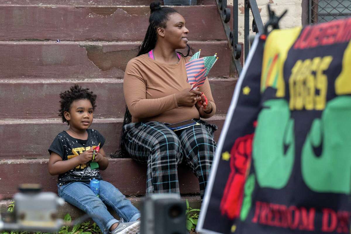 Stephanie Reeves and Hajh HeruX watch the Juneteenth parade that marched from Washington Park to the South End Grocery store on Pearl Street on Saturday, June 17, 2023, in Albany, NY.