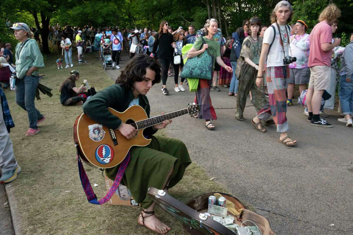 A musician plays a guitar as Dead and Company fans wait in line spanning all the way across Rt., 50 into the Shakedown Street parking lot before the last show at Saratoga Performing Arts Center on Sunday, June 18, 2023, in Saratoga Springs, N.Y. (Lori Van Buren/Times Union)