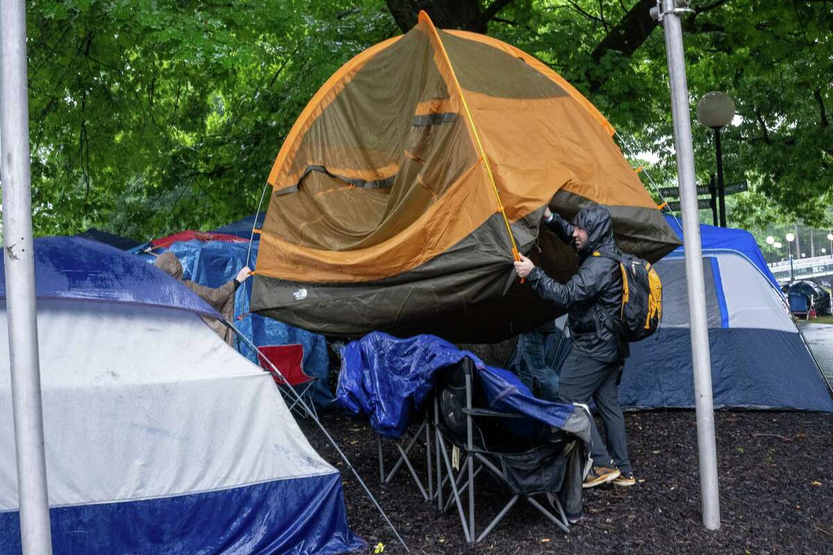 Alex Elias, Sadie Popoli and Jeremy Gold move their tent to higher ground during a rainy Freihofer’s Jazz Fest on Saturday, June 24, 2023, at the Saratoga Performing Arts Center in Saratoga, NY.