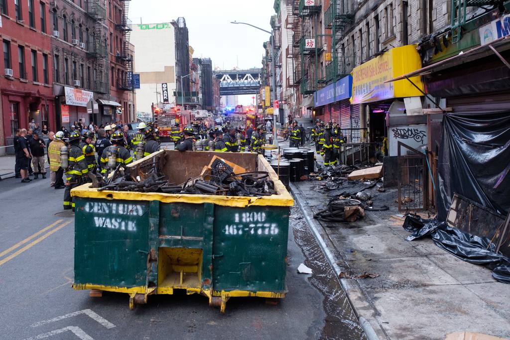 A witness said firefighters were cleaning debris from the burned-out e-bike repair shop at 80 Madison St. on Friday when lithium-ion batteries — already scorched from the blaze Tuesday that killed four people — caught fire again.