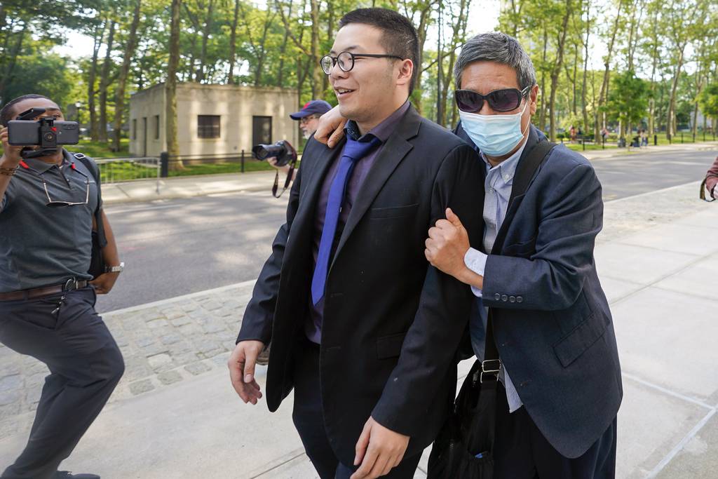 Zhu Yong, right, tries to shield himself from photographers as he leaves Brooklyn Federal court, May 31, 2023, in New York.