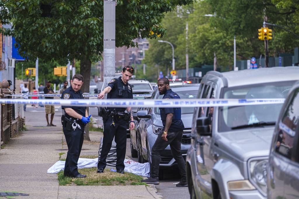 Dennis Morgan's body is covered by a bloody sheet on the sidewalk while NYPD cops gather evidence in the fatal shooting on Ashford St. in East New York, Brooklyn, Wednesday.