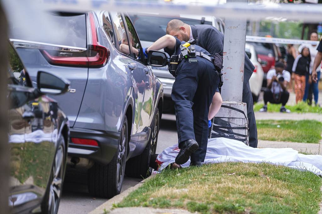 Dennis Morgan's body is covered by a bloody sheet on the sidewalk while NYPD cops gather evidence in the fatal shooting on Ashford St. in East New York, Brooklyn, Wednesday.