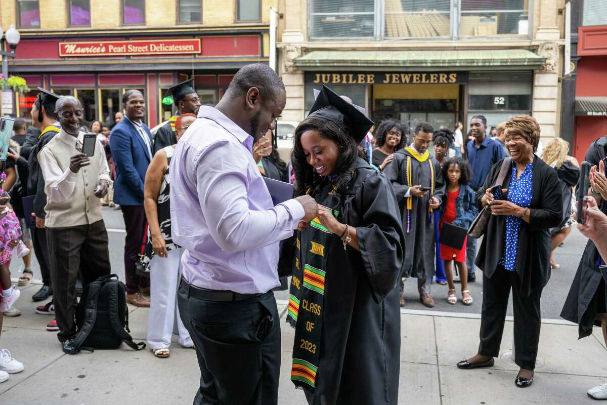 Roderick Betts III puts an engagement ring on the finger of Excelsior University graduate Symphoney Mills after her commencement ceremony on Friday at the MVP Arena in Albany.