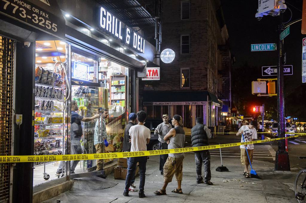 Store workers clean up broken glass outside Franklin Finest Deli after a young man was fatally shot.