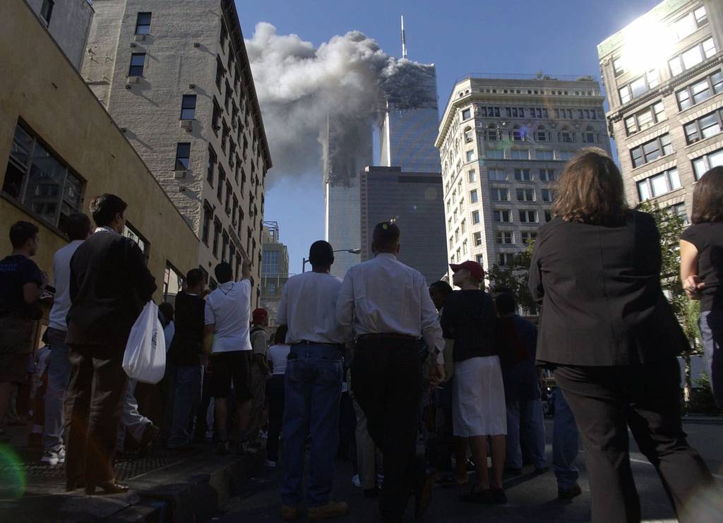 In this Tuesday, Sept. 11, 2001 file photo, pedestrians in lower Manhattan watch smoke rise from the World Trade Tower after an early morning terrorist attack on the New York landmark.