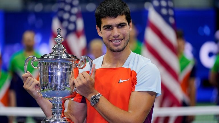 Carlos Alcaraz, of Spain, holds up the championship trophy after...