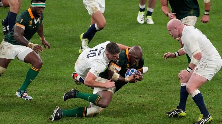 South Africa's Mbongeni Mbonambi is tackled by England's Owen Farrell...