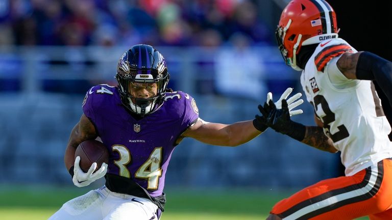 Baltimore Ravens running back Keaton Mitchell looks to run past...