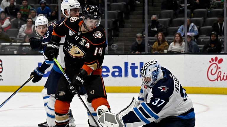 Winnipeg Jets goaltender Connor Hellebuyck, right, catches the puck in...