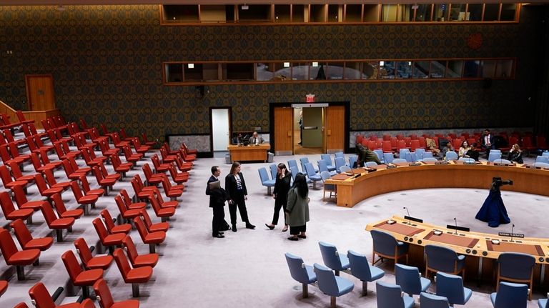 People stand in the mostly empty Security Council chambers at...