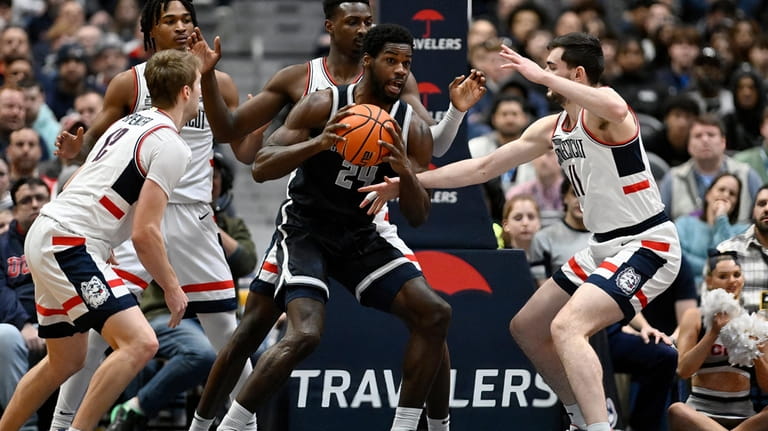 Georgetown's Supreme Cook, center, is pressured by, from left, UConn's...