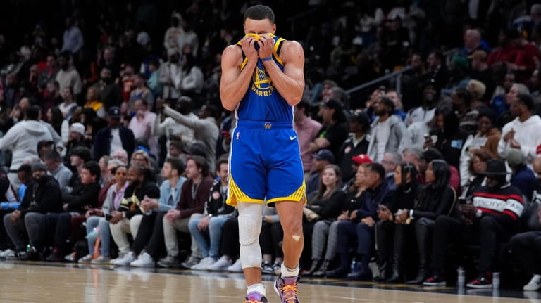 Golden State Warriors guard Stephen Curry wipes his face with...