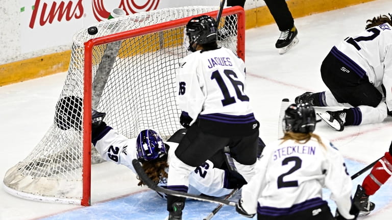 Minnesota's Nicole Hensley (29) falls backwards as the puck bounces...