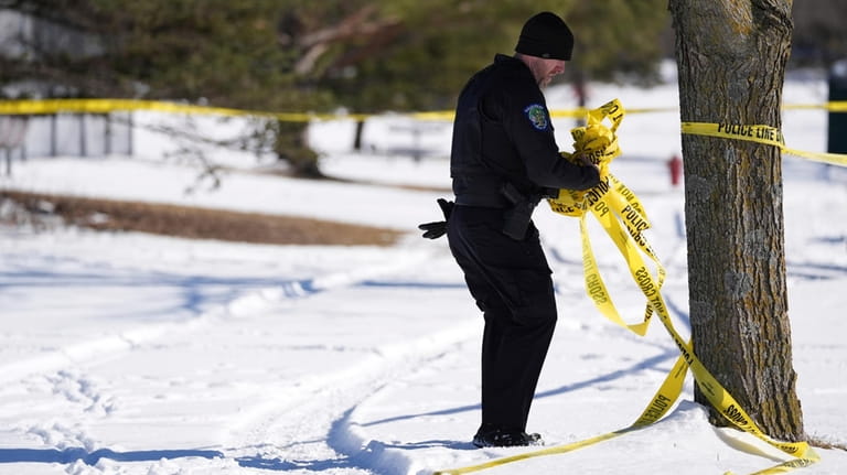 A police officer removes tape near the scene where two...