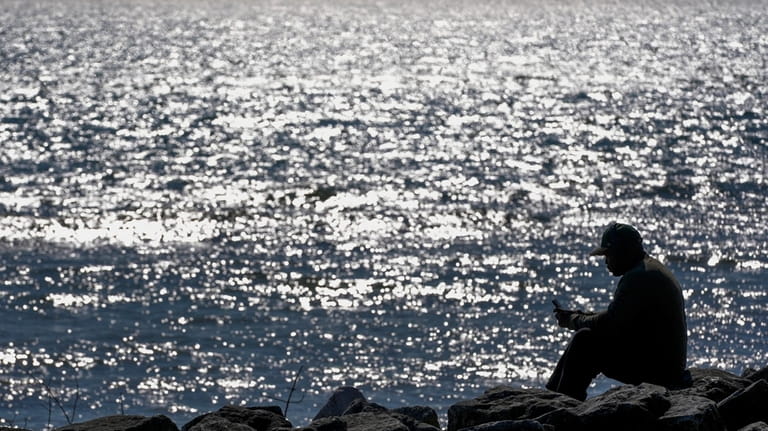 A man enjoy unseasonably warm weather along the shores of...