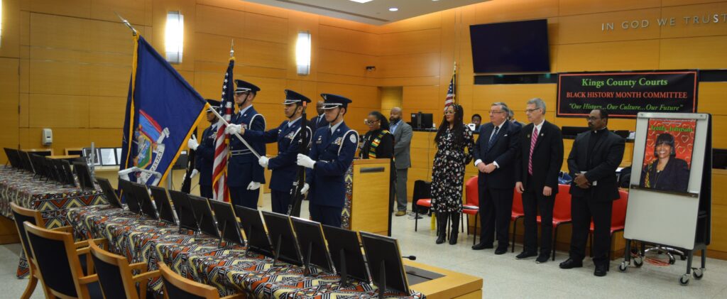 A panoramic view of the courtroom capturing the solemn presence of the color guard and the assembly of judges.