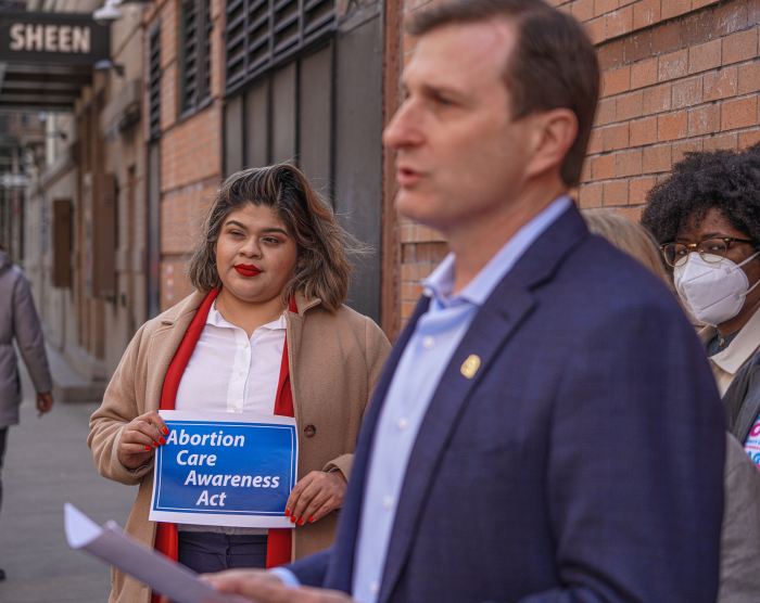 two people in front of a building discussing the Abortion Care Awareness Act