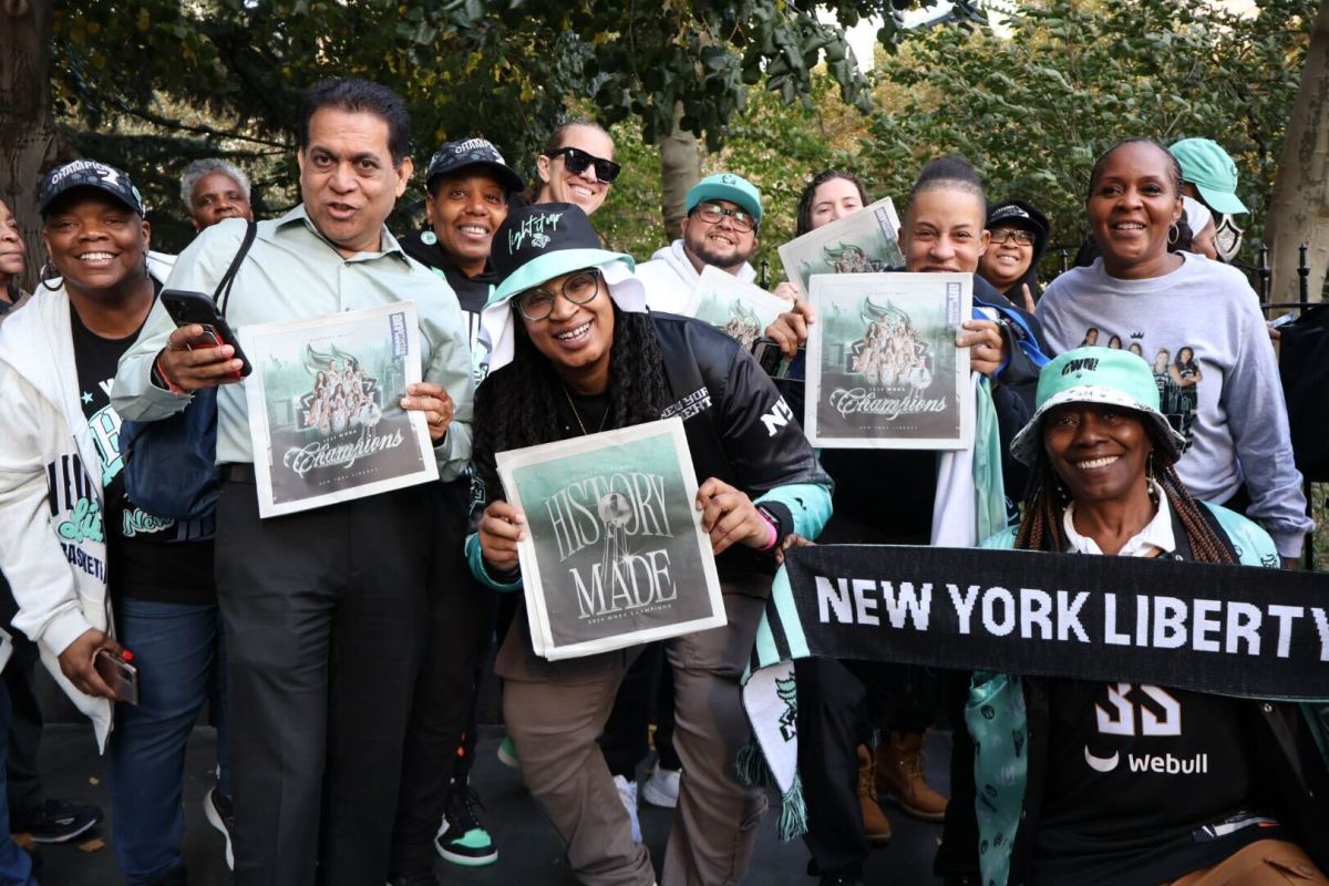 Liberty fans hold up commemorative issues of amNewYork Metro celebrating the team's first WNBA championship before the ticker tape parade in Lower Manhattan on Oct. 24, 2024.